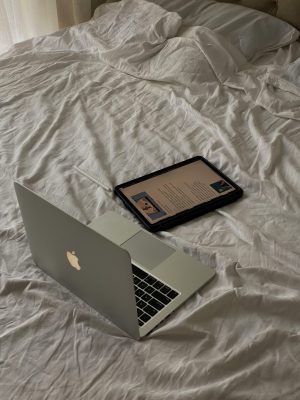 Minimalist workspace featuring a laptop and tablet on an unmade bed, depicting a casual work environment.